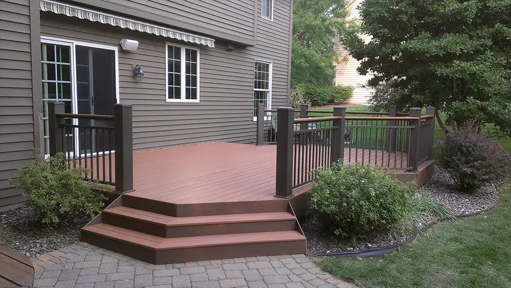 Warm brown composite deck with cascading corner steps down to a paver patio