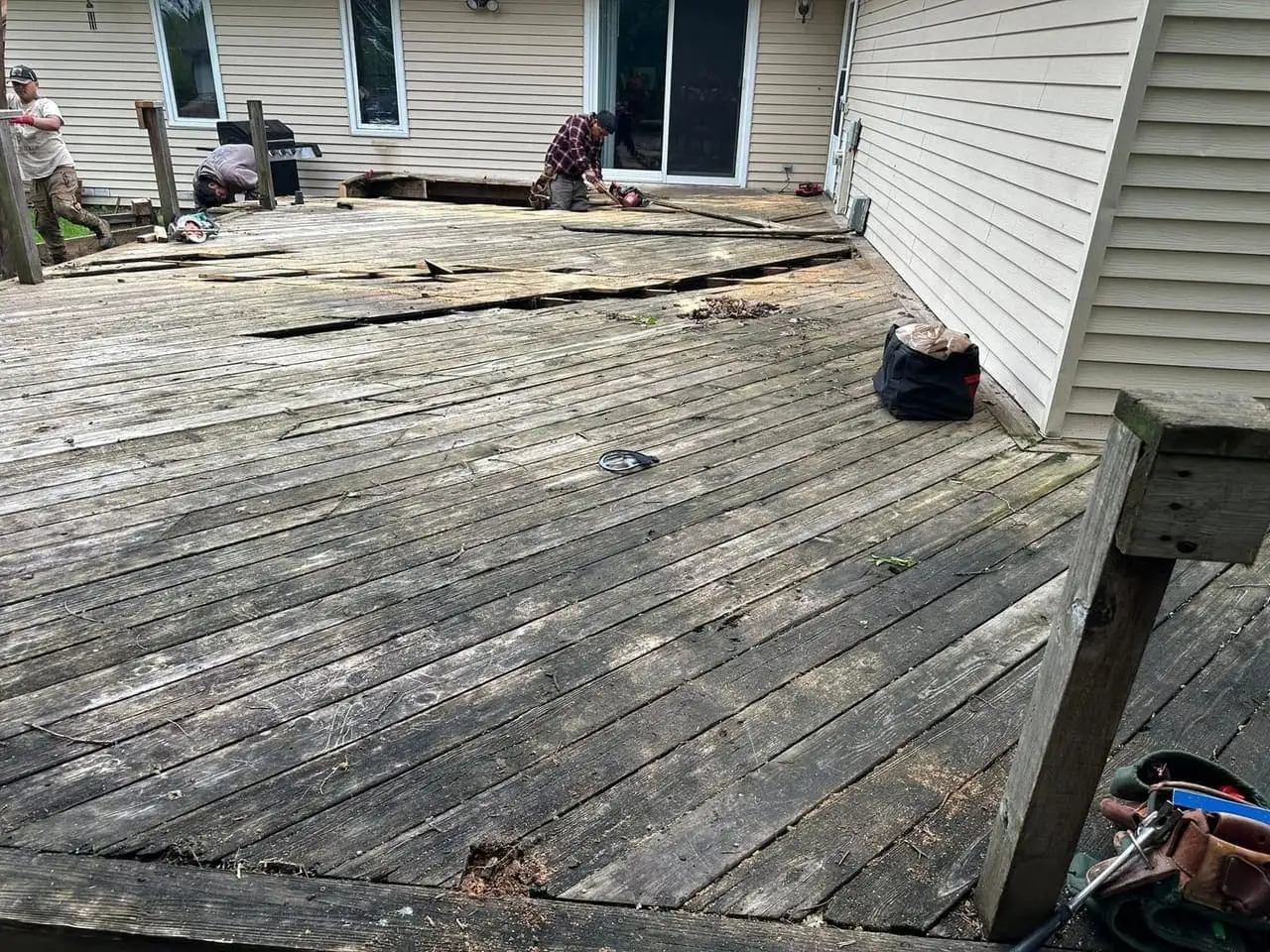 RR crew pulling the weathered grey boards off an old wood deck during a tear-out