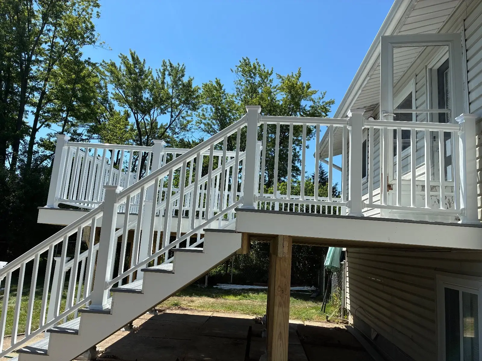 White Trex Select stair railing climbing to a new grey composite deck on 6x6 posts