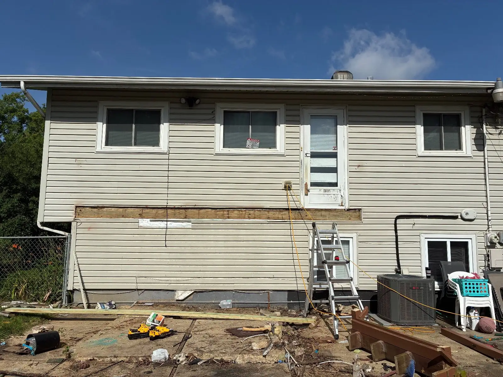The back of a raised ranch in Hoffman Estates with the old deck removed, the ledger line still visible on the siding