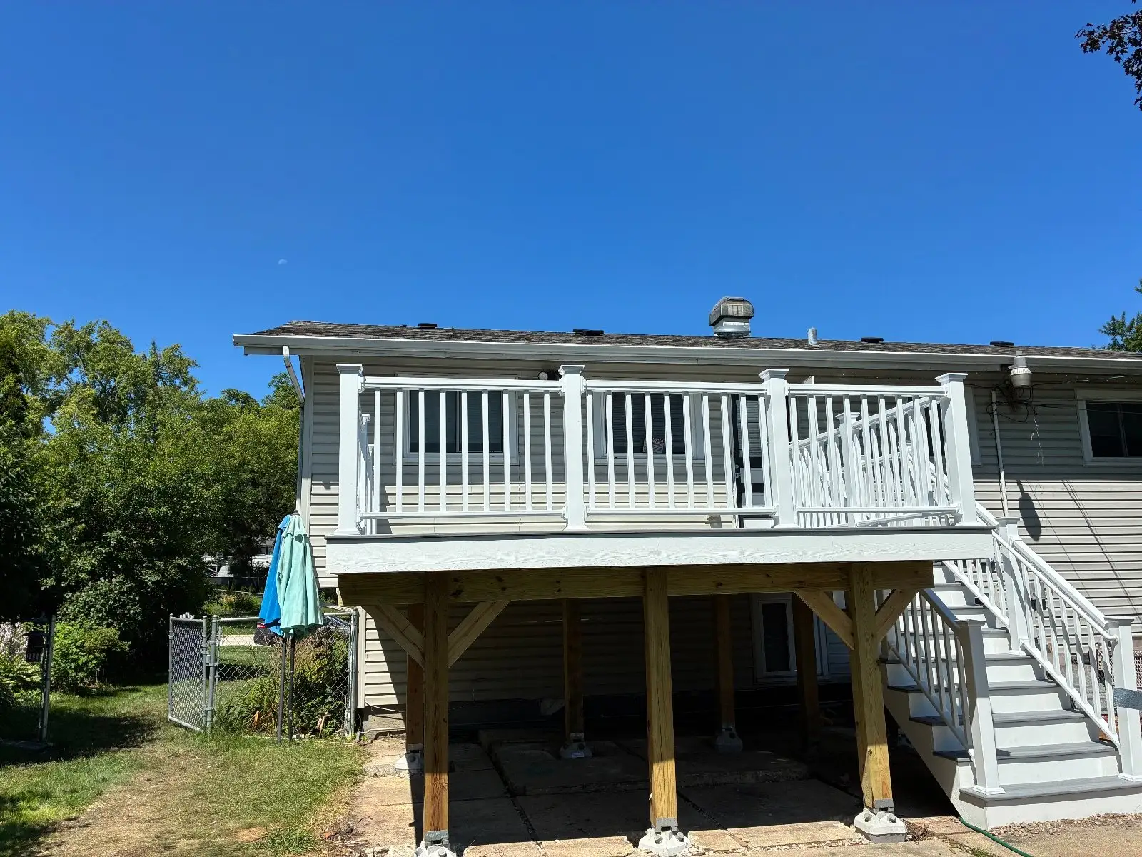 The whole back of the house with the new grey deck, white railing and stairs down to the yard