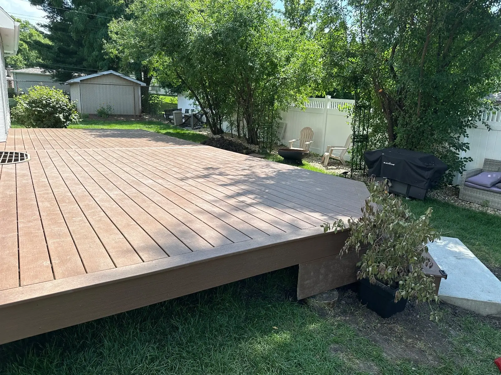 Long low Trex Whiskey Barrel deck across the back of a Lisle home, shed and white fence beyond