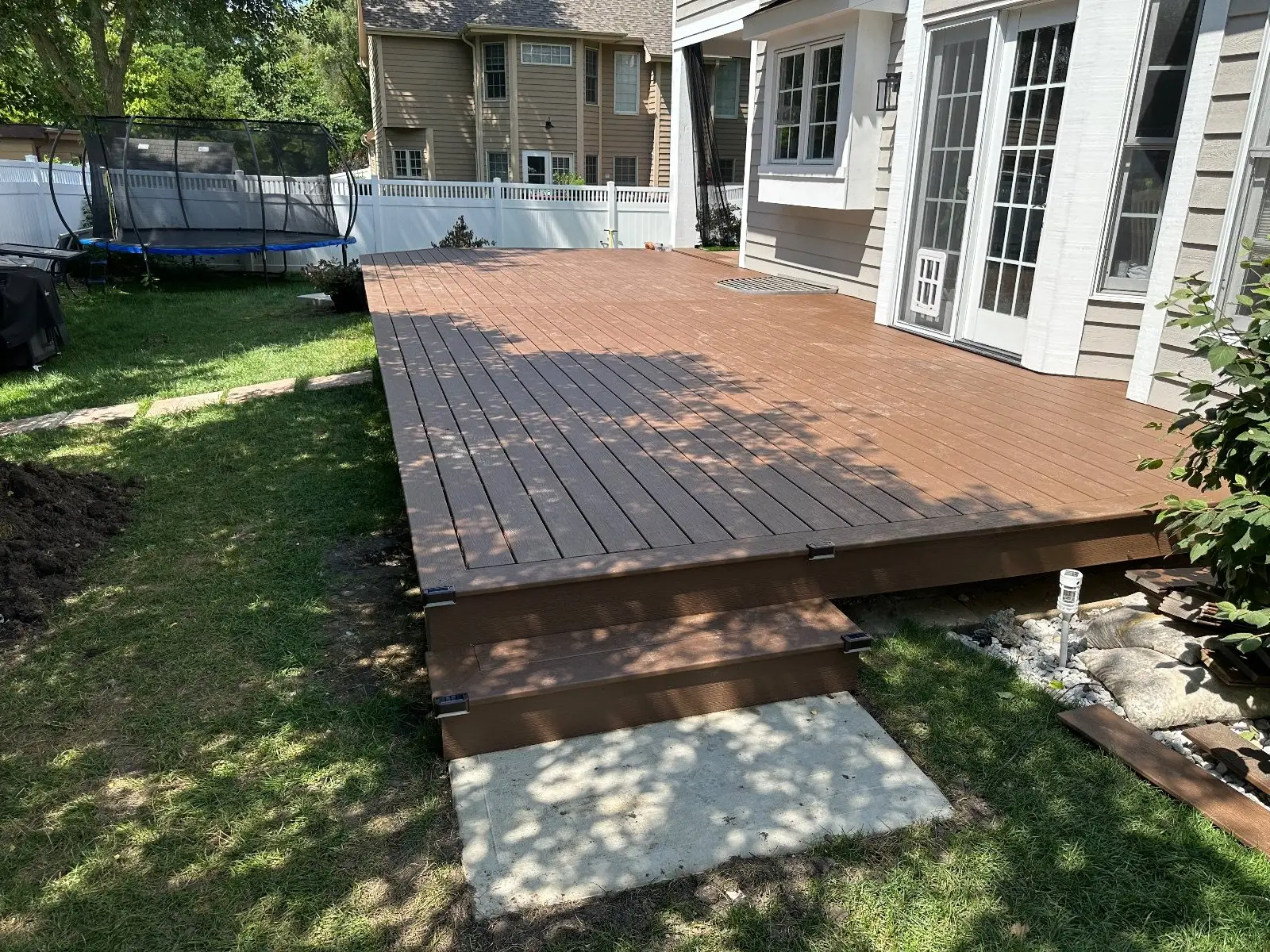 Brown Trex deck running along the house with the first step down to a concrete landing
