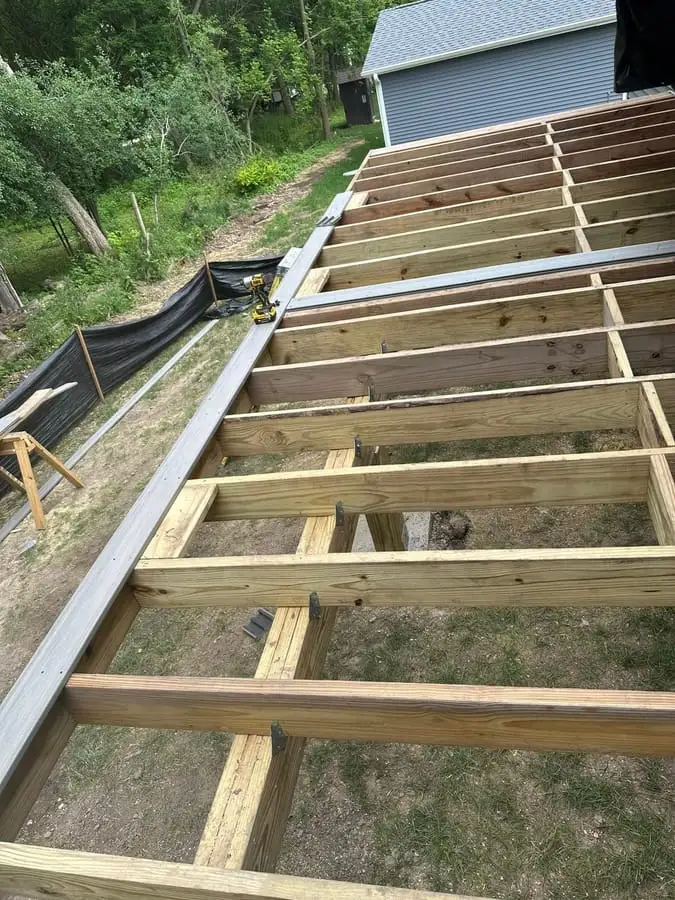 Pressure-treated deck framing and joists going in over a sloped yard before decking is installed