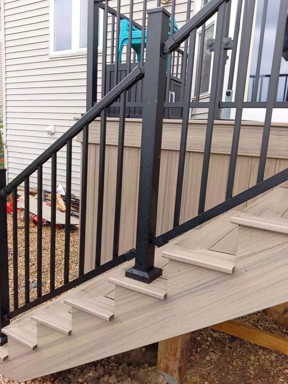 Black aluminum railing post and balusters mounted on light composite stair treads