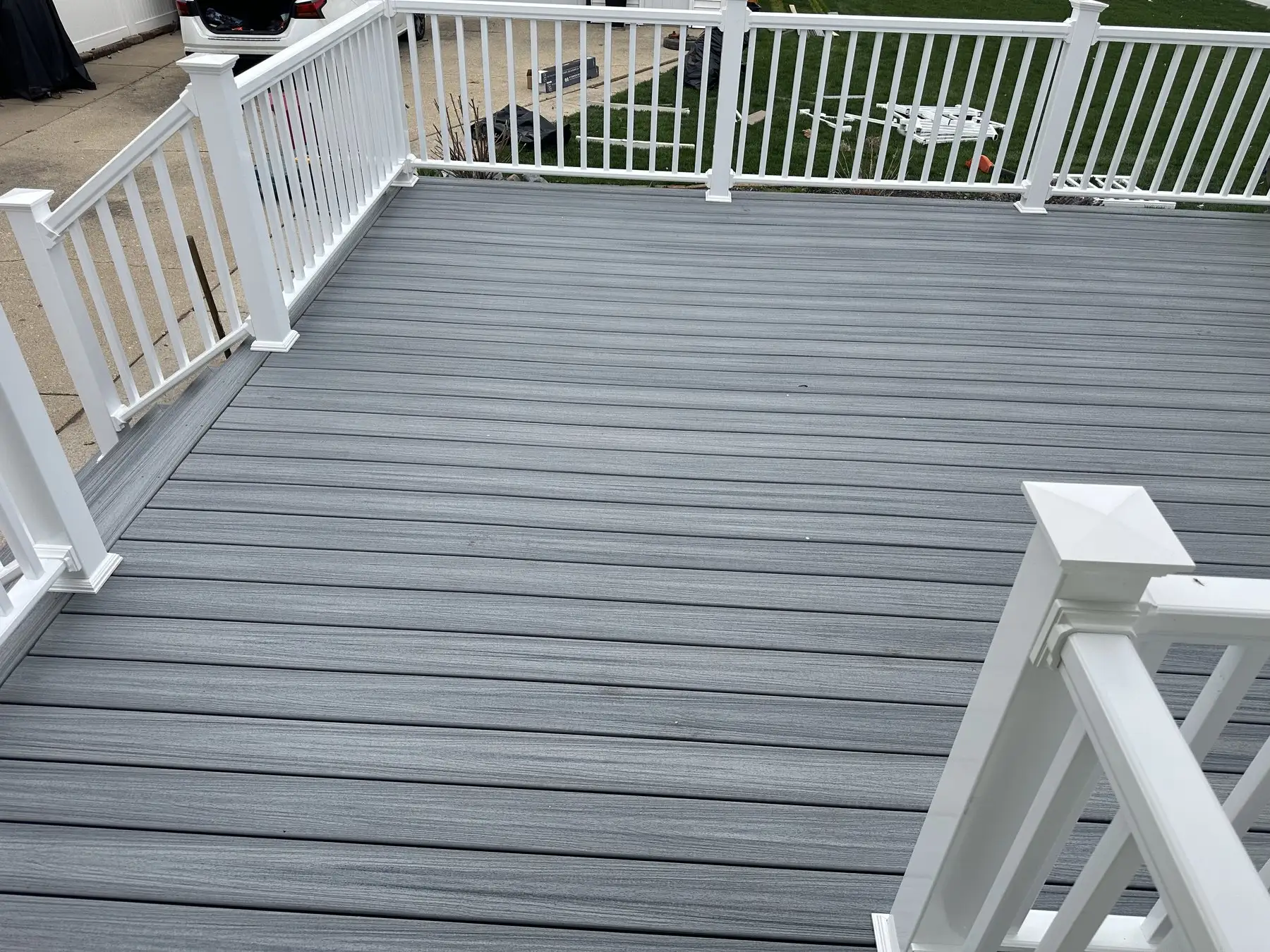 The same deck rebuilt in grey composite with white railings and a white corner post