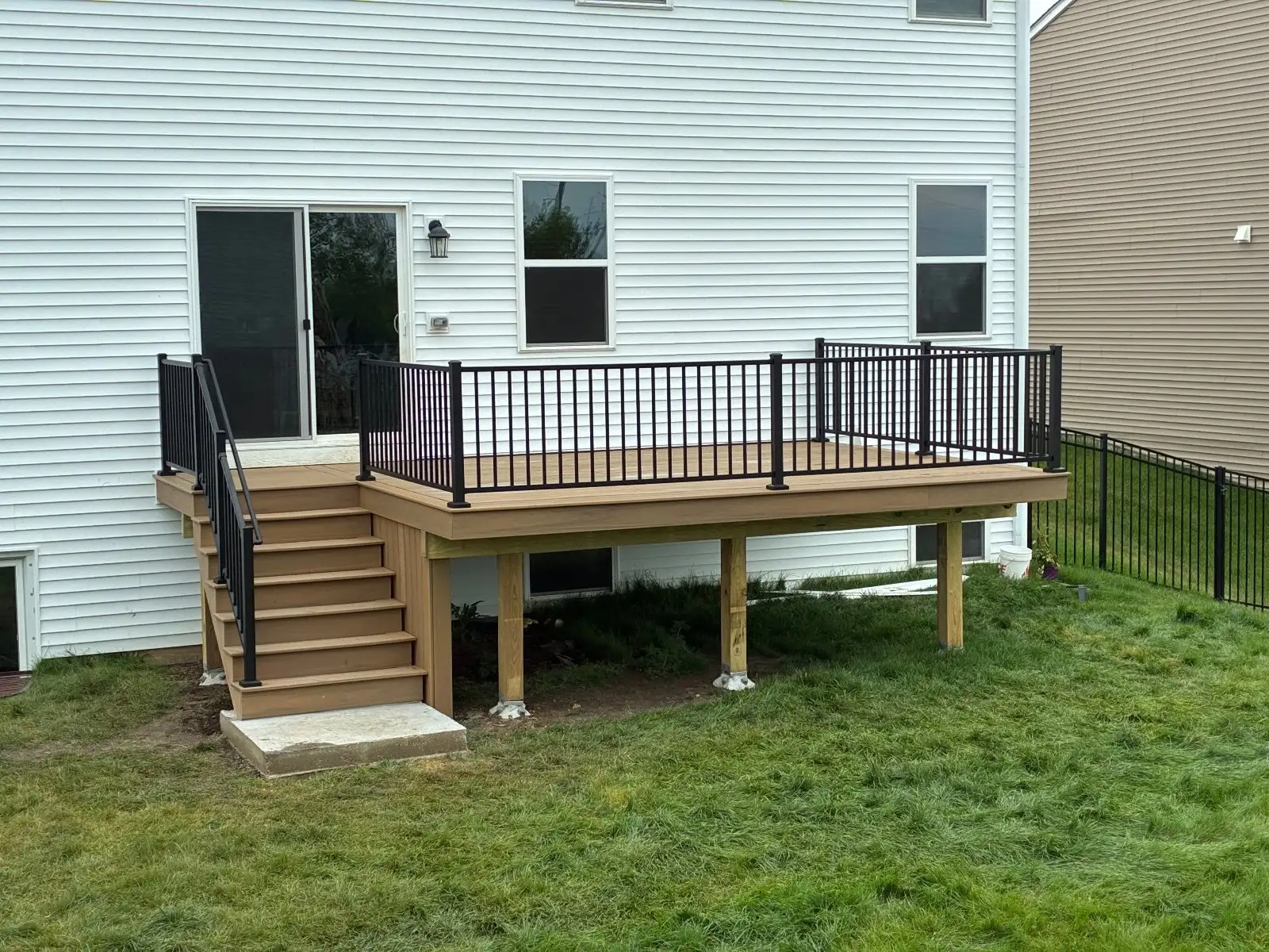 TimberTech Coconut Husk deck with black Trex Select railing and stairs down to a concrete pad in South Elgin
