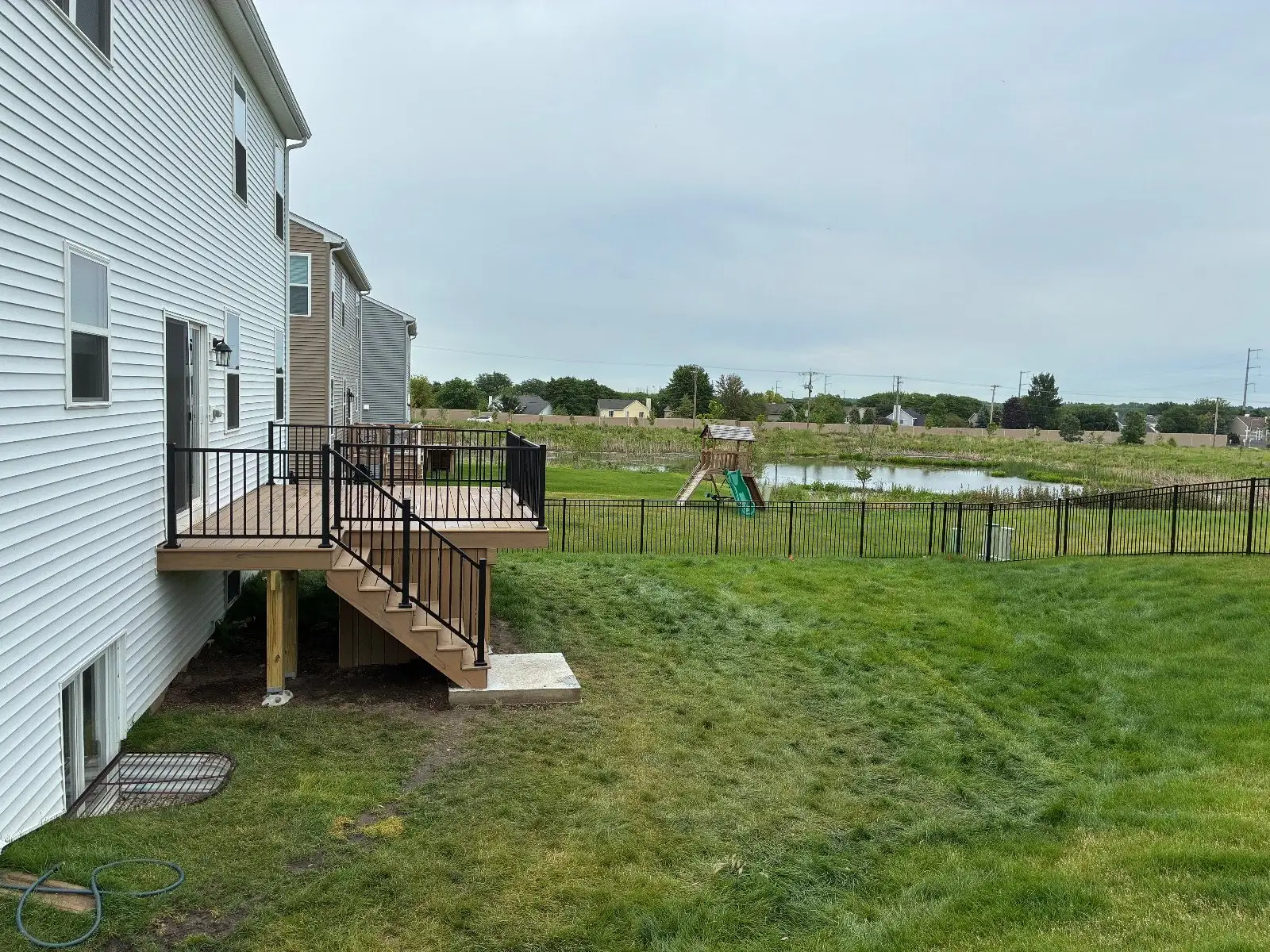 The South Elgin deck from the side with the pond and a play set behind the fence