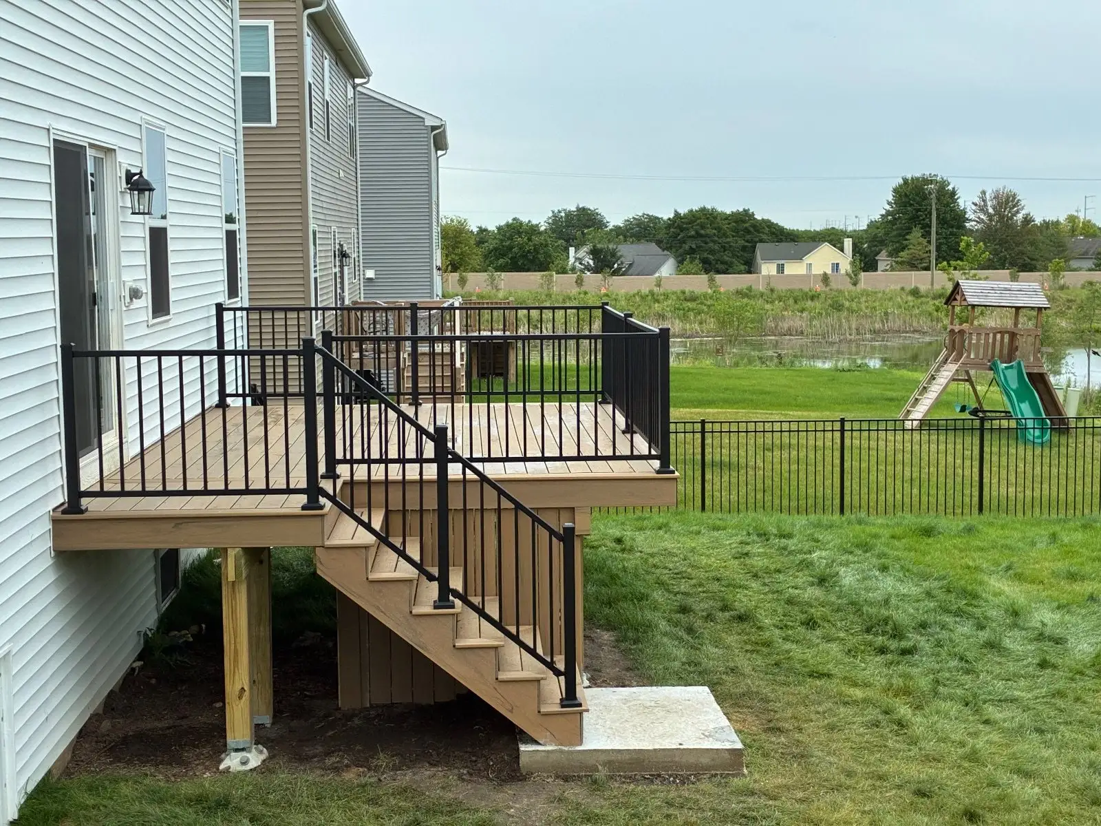 The deck and stairs from the yard side, looking across the lawn to the pond